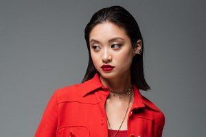 Stunning Asian woman wearing a red suit with slicked back, smooth mid-length hairstyle